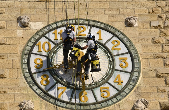 Operai acrobati smontano le lancette alla torre dei caduti di Bergamo
