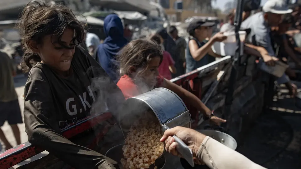Bambini ricevono cibo da una cucina per gli sfollati nella città di Gaza