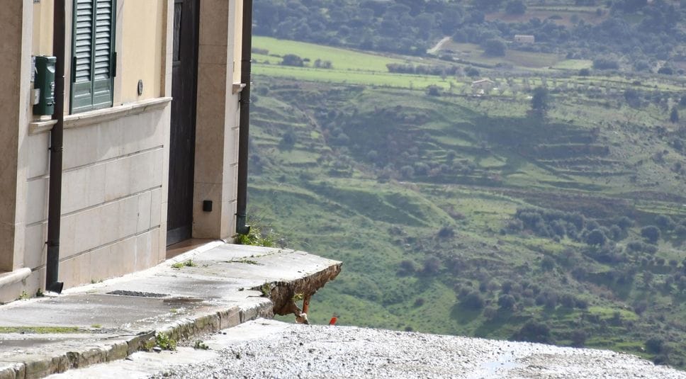 Una strada di Niscemi interrotta dalla frana: le case ora sono sull’orlo del baratro