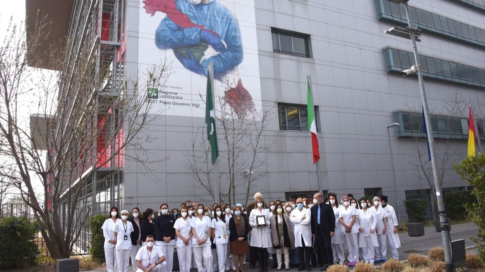 Personale del «Papa Giovanni» davanti all’immagine simbolo della lotta al Covid, in una foto d’archivio